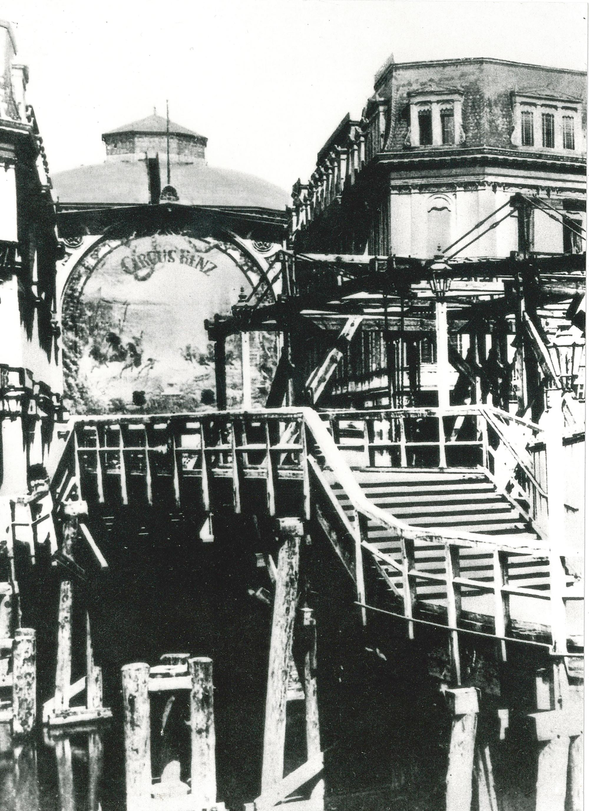 Der Kuppelbau des Markthallenzirkus unter Circus Renz, im Vordergrund die Holzbrücke nahe der Pankemündung in die Spree (ca. 1890).