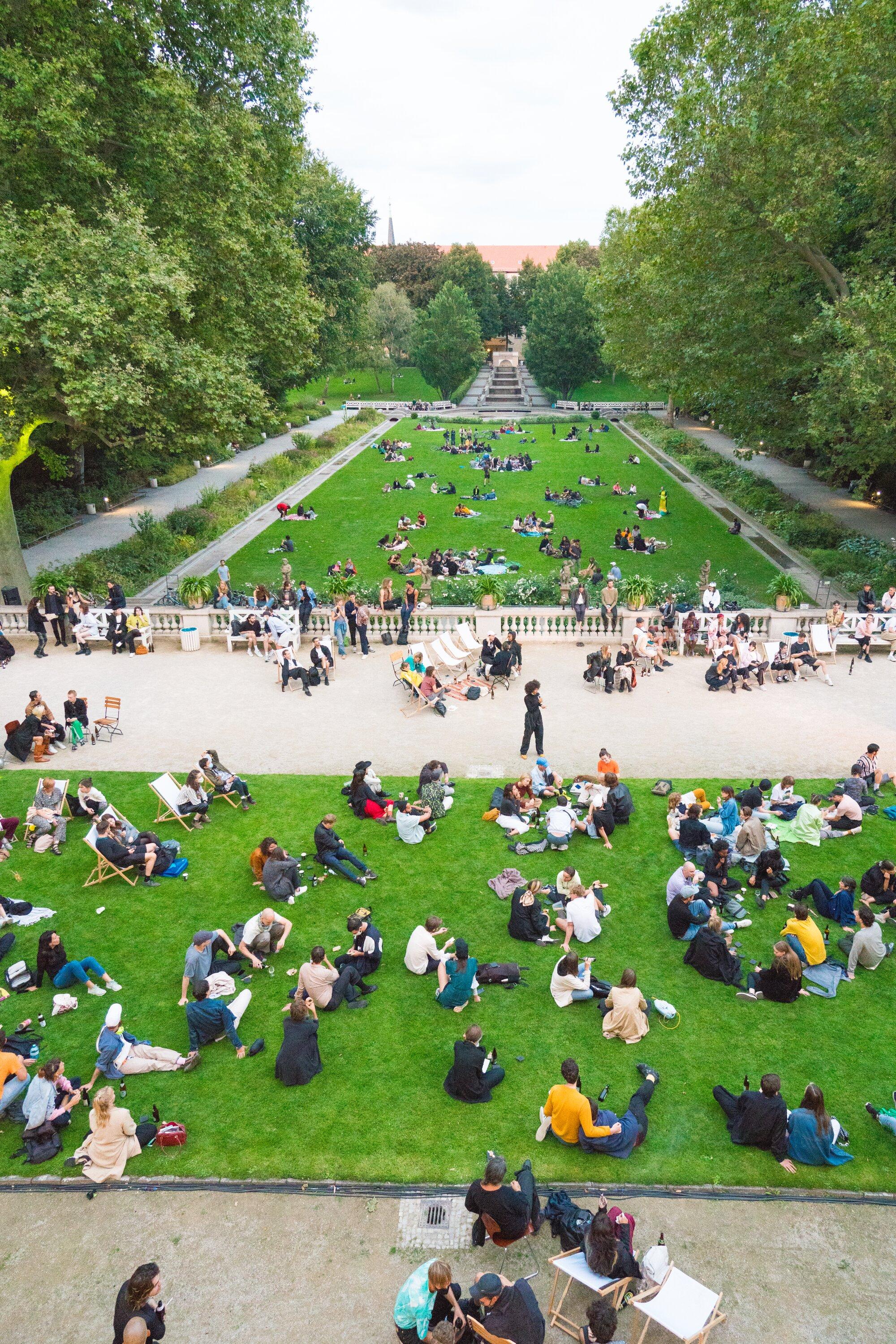 Isabel Lewis in Körnerpark, Neukölln – she is the standing figure in the centre of the image. This is what Isabel’s “hosted occasions” looked like during the Covid pandemic. Isabel Lewis, An occasion to consider celebration futures, with Juliana Huxtable and Mars Dietz, food by Chelsea Turowsky, smells by Sissel Tolaas, 3hd 2020: UNHUMANITY, Körnerpark, Berlin.