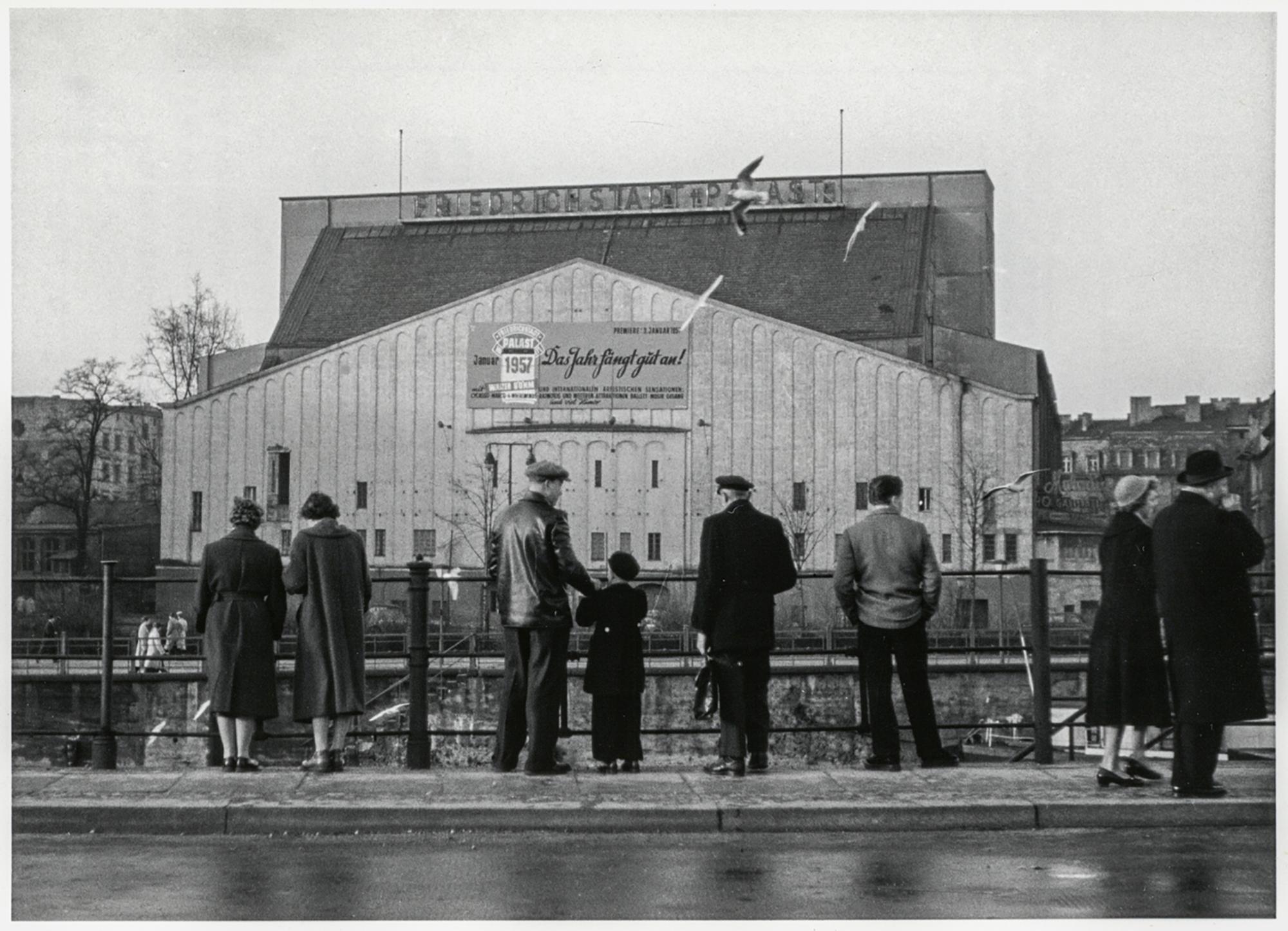 Passant:innen blicken vom gegenüberliegenden Spreeufer auf den einstigen Markthallenzirkus, inzwischen als Friedrichstadt-Palast (1957).