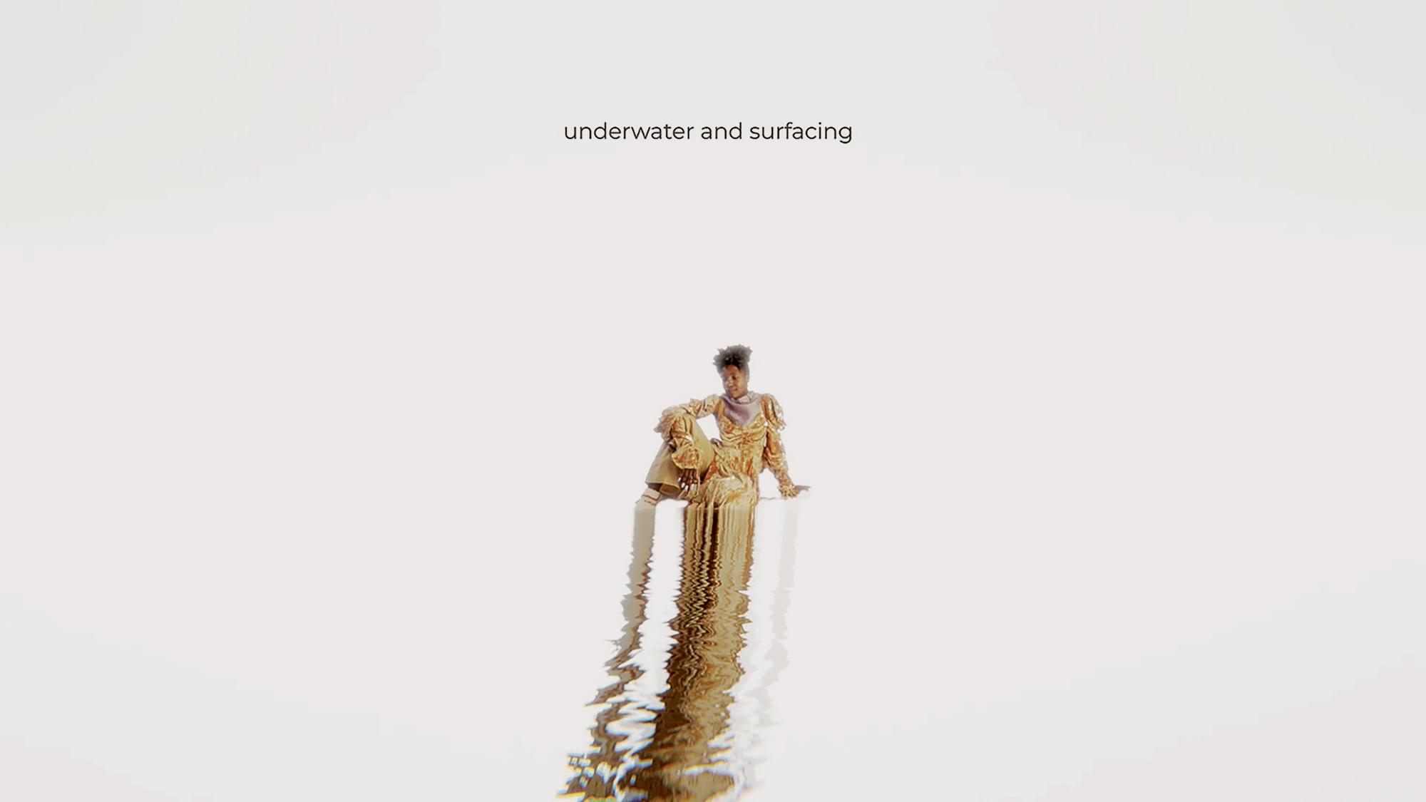Dancer Rudzani Moleya, a medium-toned black woman, wears a long mustard yellow tunic and has her hair pinned up. They are sitting in the distance within a white background. Their reflection ripples all the way in a thin line across the screen. The words »underwater and surfacing our soil« appear above her head. Alexandrina Hemsley: Fountain, 2022, image description taken from social media of the artist.