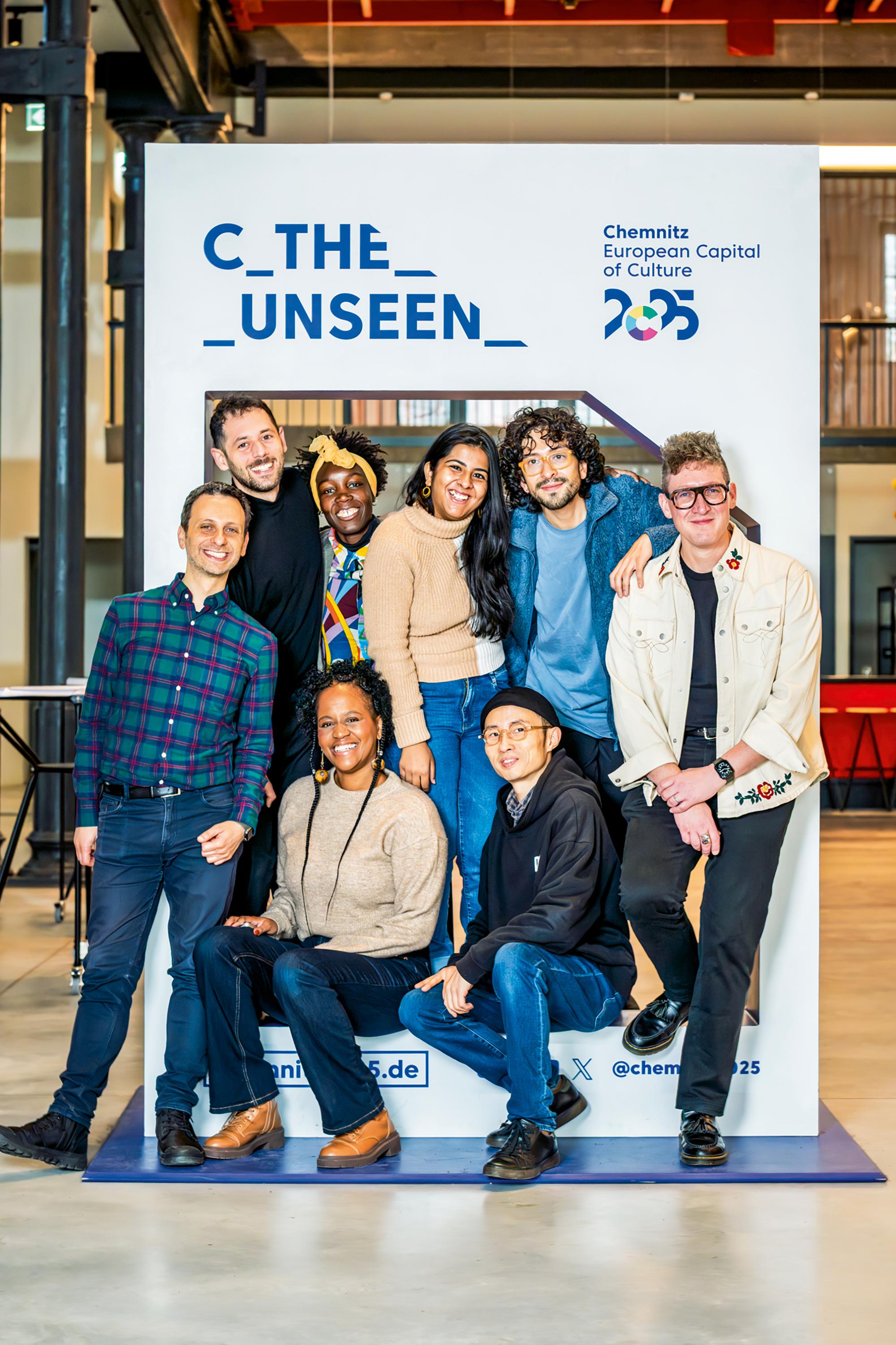 Sie kuratieren Theater der Welt in Chemnitz: Nikos Mavrakis (Griechenland), Faye Kabali-Kagwa (Südafrika), Yuan Zhang (China) und Joshua Dalledonne (Kanada), dahinter Simon Abrahams (Australien), Ndèye Mané Touré (Senegal), Srishti Ray (Indien) und Rodrigo González Alvarado (Kolumbien, Argentinien). Auf dem Bild fehlt Aya Nabulsi (Jordanien, Saudi-Arabien)